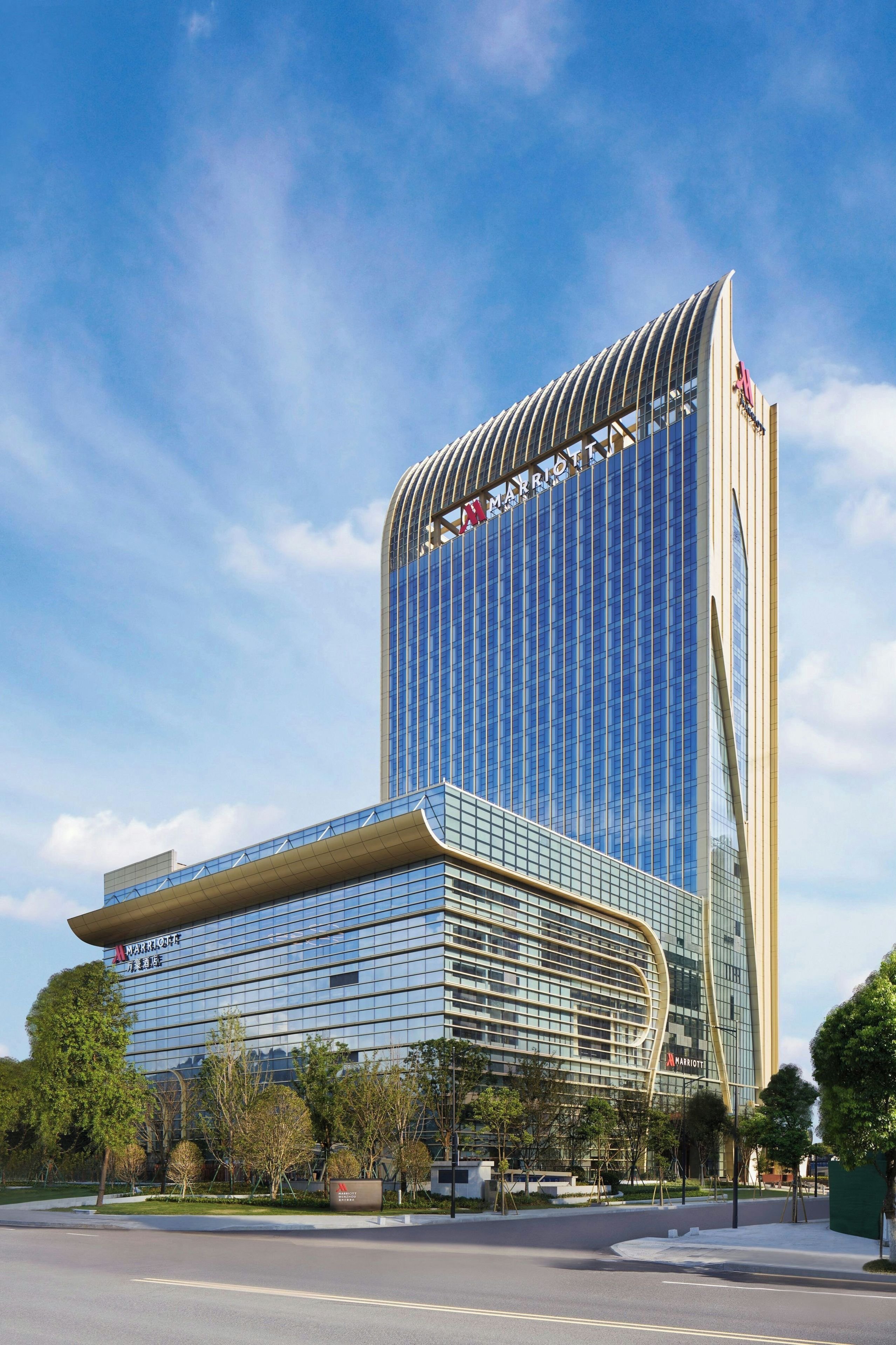 A modern hotel with a curved glass facade and a prominent 'Marriott' sign.