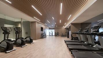Un gimnasio moderno con cintas de correr, elípticas y equipo de pesas.