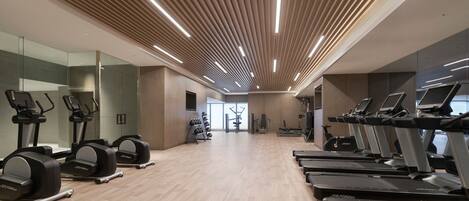 A modern gym with treadmills, elliptical machines, and weight equipment.