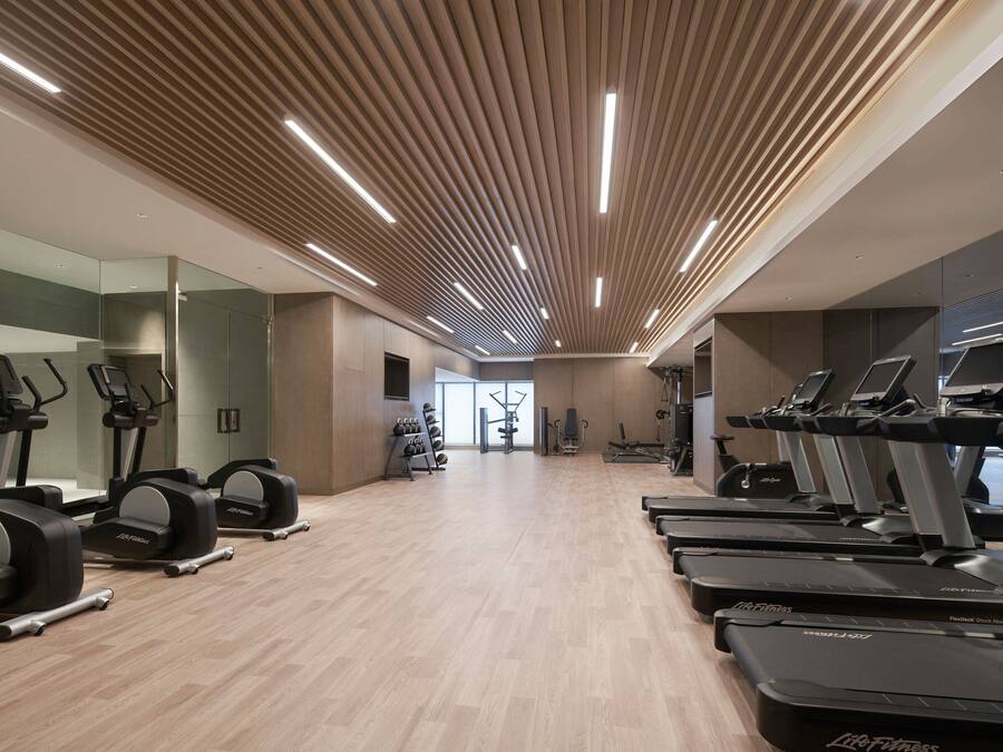 Un gimnasio moderno con cintas de correr, elípticas y equipo de pesas.