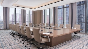 A conference room with a long table, multiple chairs, and large windows offering a city view. - Jinhua Marriott Hotel (Jinhua)