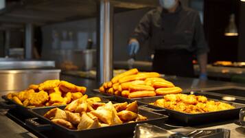 Un buffet con diversi piatti, tra cui samosa e altri snack fritti.