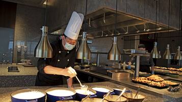 Un chef preparando comida en una cocina moderna con electrodomésticos de acero inoxidable y una barra de buffet.