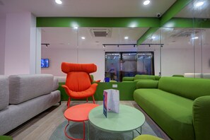 Un área de espera moderna con un sofá verde, una silla roja y un sofá gris.