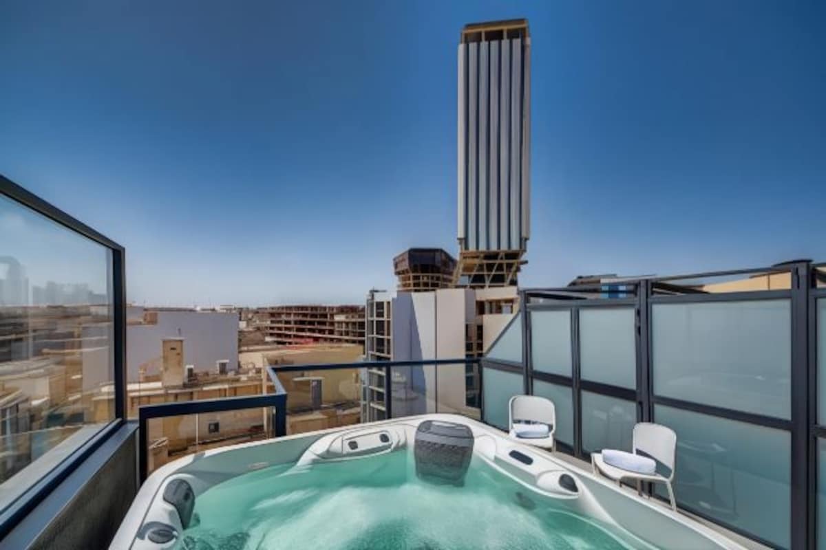 Terraza en la azotea con jacuzzi, zona de estar y vistas a la ciudad.