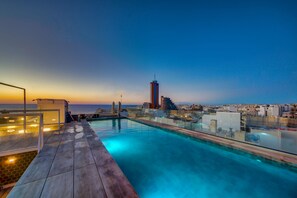 A rooftop pool with a cityscape view at sunset. - IKYK Hotel - IK Collection (St. Julian's)