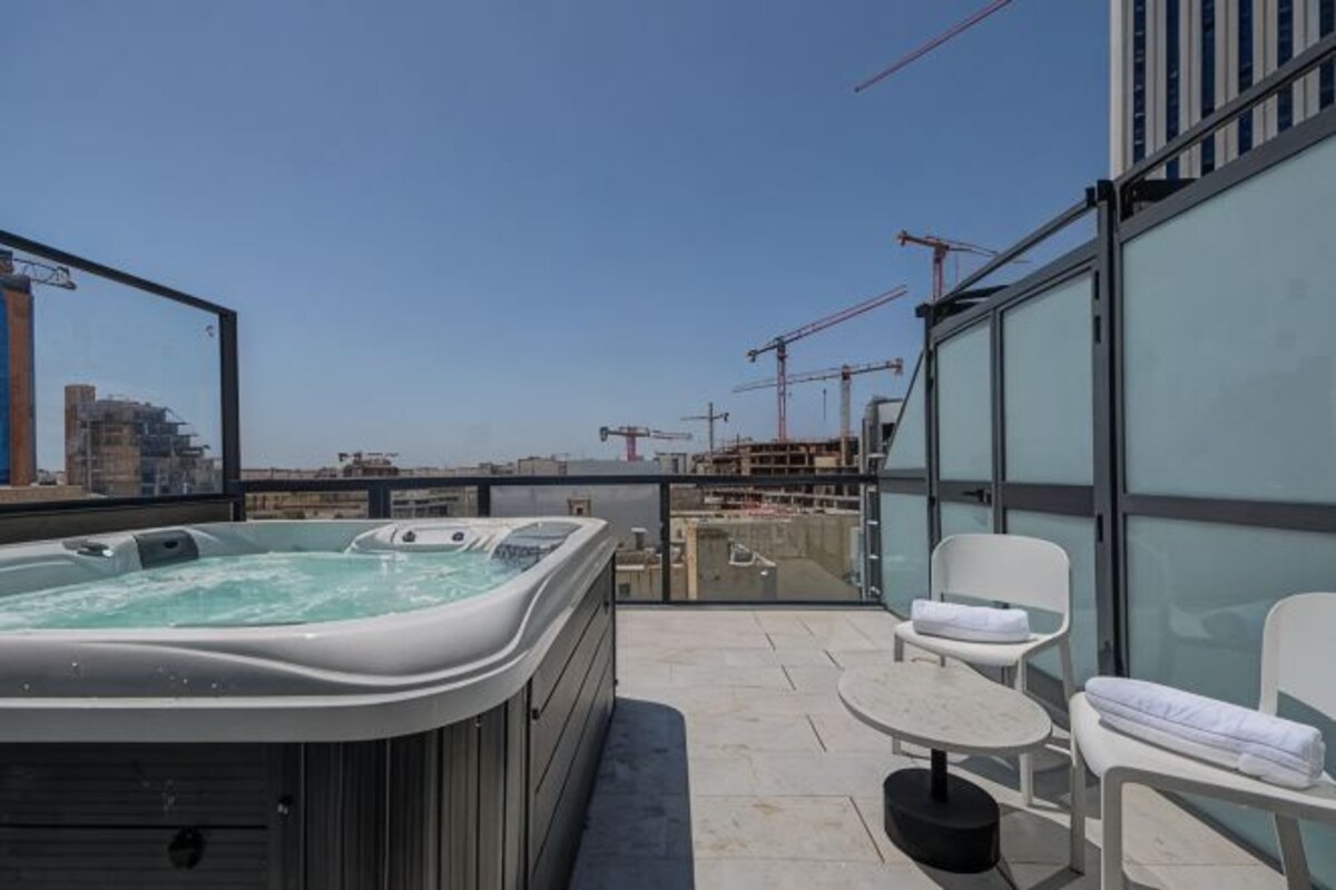 Terraza en la azotea con jacuzzi, zona de estar y vistas a la ciudad.