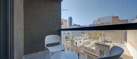 Un balcón con vistas a la ciudad, que incluye una mesa y dos sillas.