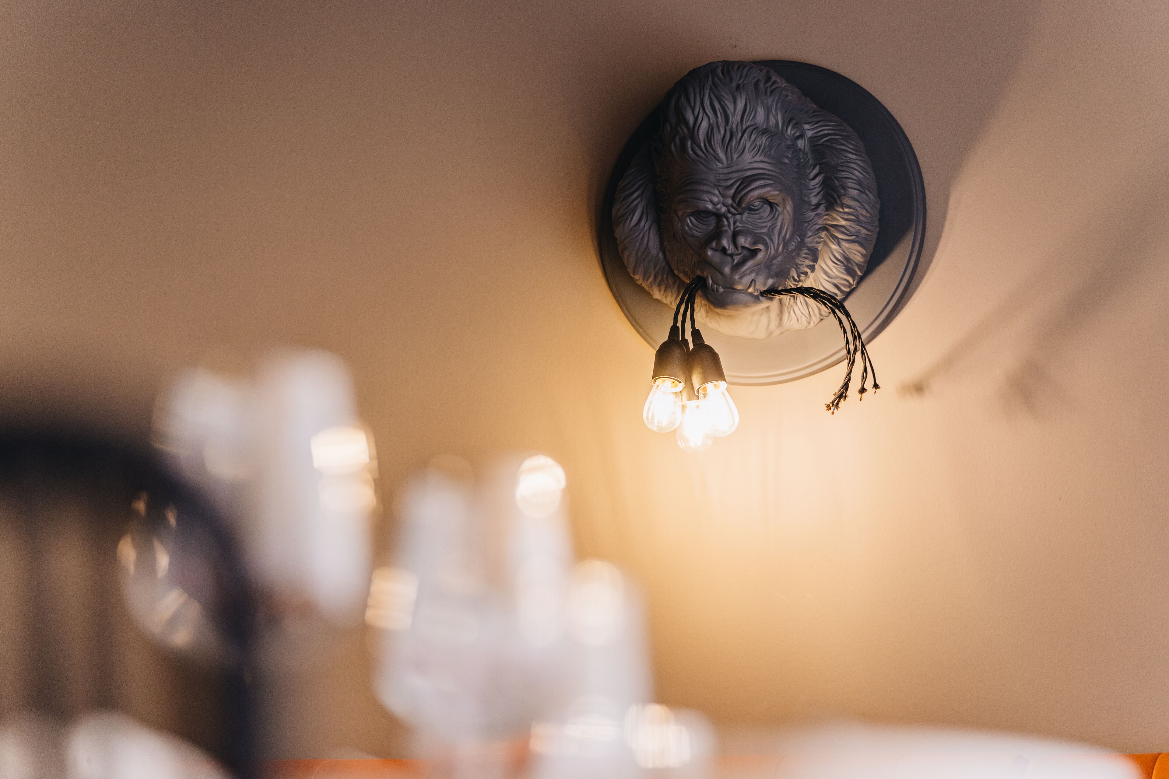 A wall-mounted light fixture with a decorative headpiece and two hanging bulbs.