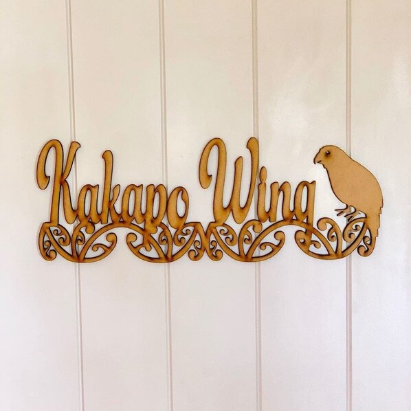 A decorative wooden sign with the text "Kakapo Wing" and a bird silhouette.