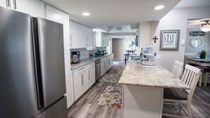 A modern kitchen with stainless steel appliances, white cabinetry, and a central island with seating. - Prinstine 4BR Havasu Home — Tons of Boat Parking & Dual AC (Lake Havasu City)