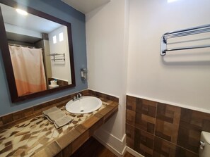 A bathroom with a white sink, a mirror, a towel rack, and a shower curtain.