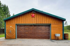 A wooden garage with a brown door, a red star decoration, and a wheel on the wall.