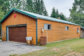 A wooden building with a garage, a small window, and a metal barrel. - Arkdale Studio Cabin w/ On-Site ATV Trails! (Arkdale)
