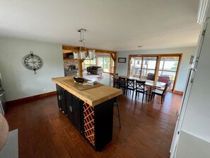 A spacious kitchen with a central island, wooden flooring, and a dining area with a view. - Need a summer getaway? Book NorthFork Lakehouse-the ultimate cottage destination (Sebright)