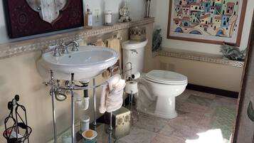 Une salle de bain avec un grand miroir, un lavabo, des toilettes et un espace douche.