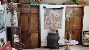 Una sala de estar acogedora con un sofá de madera, una mesita con un florero y un mueble grande de madera.