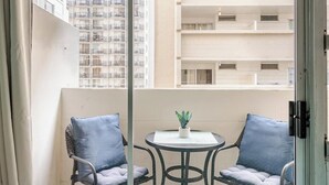 Un balcon avec deux chaises, une petite table et un pot de fleurs.