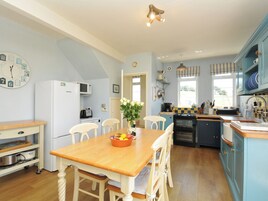 Una cocina con una mesa de madera, sillas, un refrigerador, un microondas y una estufa.