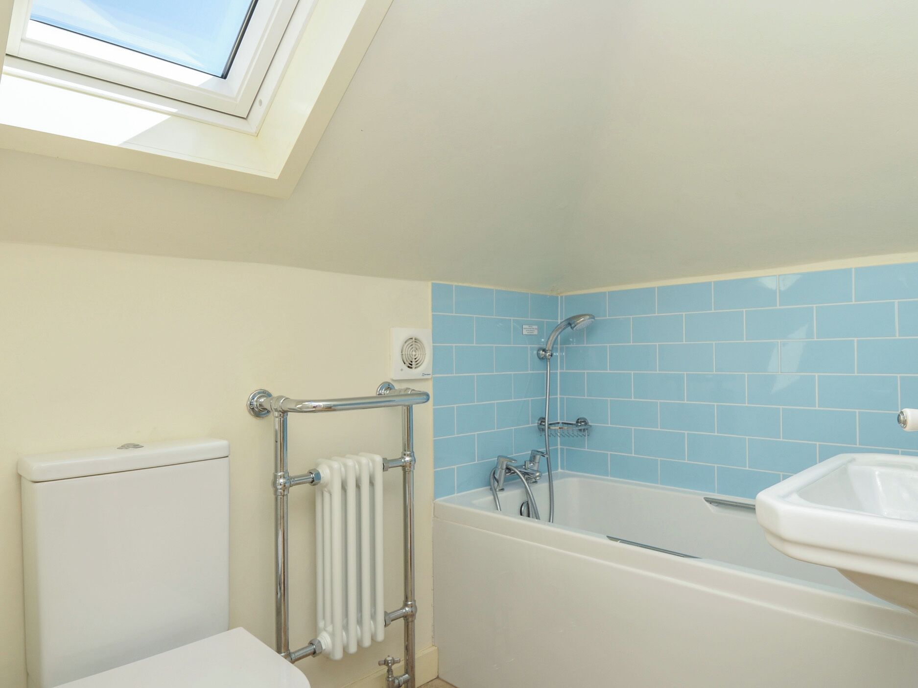 Een badkamer met dakraam, bad, douche en wastafel.
