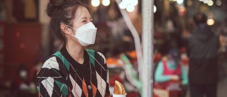 A person holding a baguette at a market stall with a sign above.