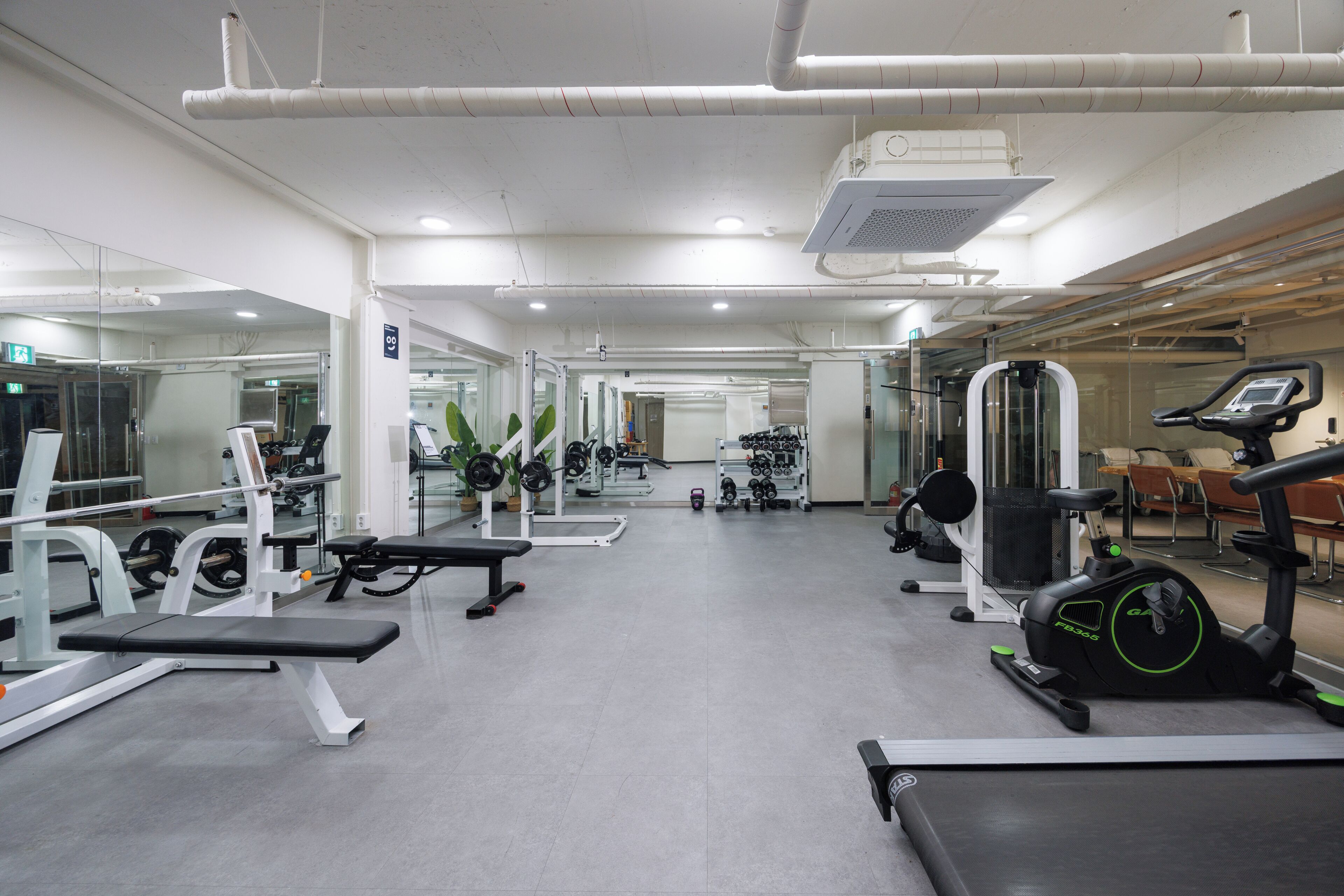 A gym with various exercise equipment, including treadmills, weight machines, and free weights.