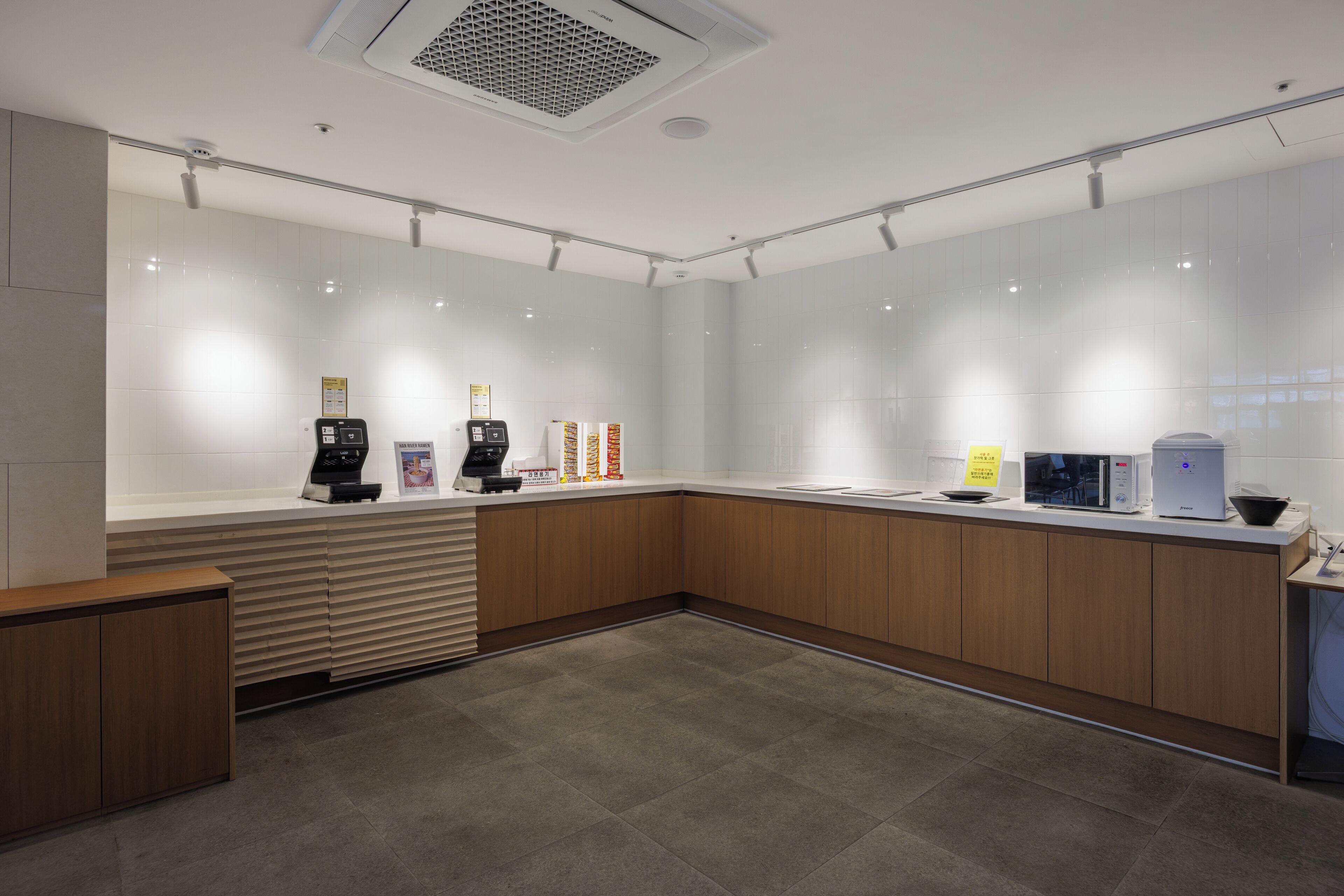 A modern kitchen with a built-in microwave, coffee machine, and a kettle on the counter.