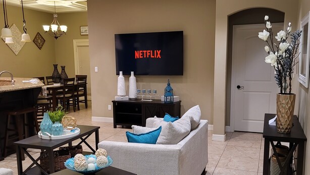 A living room with a sofa, coffee table, and TV displaying 'NETFLIX'. - Isabella's getaway (Edinburg)