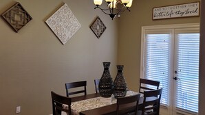 A dining area with a chandelier, decorative wall pieces, and a door with blinds. - Isabella's getaway (Edinburg)