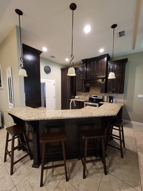 A kitchen with a large island, dark wooden cabinets, and pendant lighting. - Isabella's getaway (Edinburg)