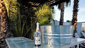 A glass table with a bottle of sparkling wine and a wine glass.