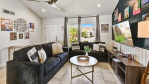 A modern living room with two dark sofas, a coffee table, and artwork on the walls.