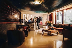 A cozy lobby with a bar area, seating, and a decorative vase with flowers.