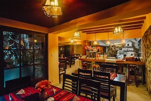 A restaurant with multiple dining tables, chairs, and hanging pendant lights.