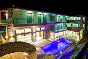 A multi-story hotel with a pool, outdoor seating, and a stone facade. - Core Hotel (Kassandra)