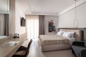 A modern hotel room with a bed, a desk, a chair, a television, and a painting on the wall. - Core Hotel (Kassandra)