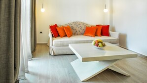 A modern living room with a sofa, orange cushions, a coffee table with fruit, and hanging pendant lights. - Core Hotel (Kassandra)