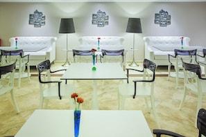 A hotel room with a white sofa set, a dining table with chairs, and a wall adorned with framed photographs. - Core Hotel (Kassandra)
