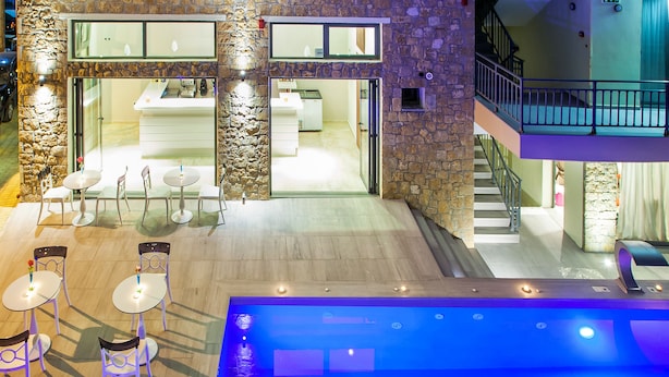 A pool area with seating and a view of a restaurant and kitchen. - Core Hotel (Kassandra)
