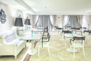A hotel dining area with white furniture, including sofas and tables, and a chandelier. - Core Hotel (Kassandra)