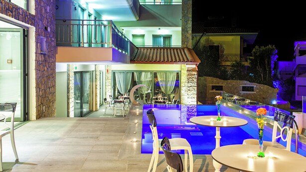 Ein moderner Poolbereich im Freien mit Essbereich und einer Treppe, die zu einem Balkon führt.