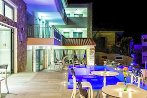 A modern outdoor pool area with a dining setup and a staircase leading to a balcony. - Core Hotel (Kassandra)