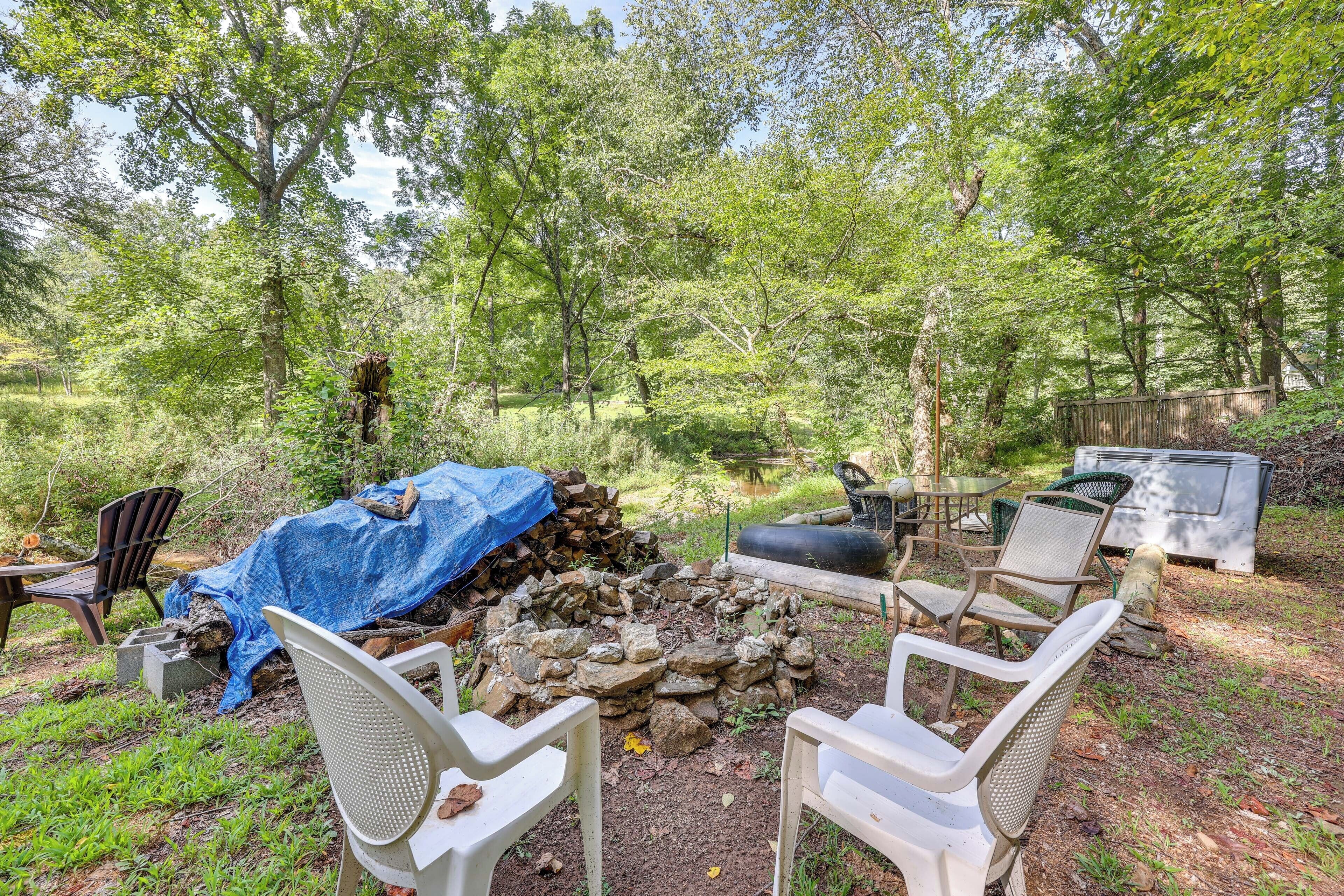 An outdoor seating area with chairs and a fire pit surrounded by trees.