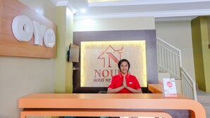 A hotel reception desk with a sign reading "Oyo" and "NOUV" indicating guest services. - OYO 809 Noura Guest House Syariah (Malang)