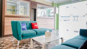 A teal sofa with a YouTube pillow, a white coffee table, and a check box. - OYO 809 Noura Guest House Syariah (Malang)