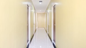 A long, narrow hallway with doors on both sides, leading to individual rooms. - OYO 809 Noura Guest House Syariah (Malang)