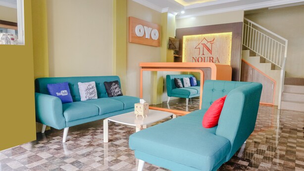 A hotel lobby with teal sofas, a checkered floor, and a staircase. - OYO 809 Noura Guest House Syariah (Malang)