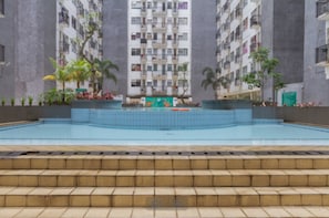 Piscina com degraus de acesso, cercada por edifícios de apartamentos.