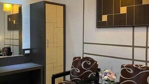 A modern room with a large mirror, a wardrobe, and a seating area with a floral arrangement. - Bukit Indah Lestari Hotel (Tanjung Baru)