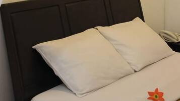 A bed with a dark headboard and two pillows.